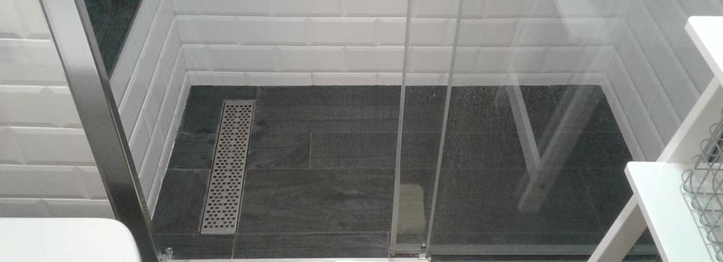 Plato de ducha de obra con suelo porcelánico imitación parquet y desagüe con rejilla